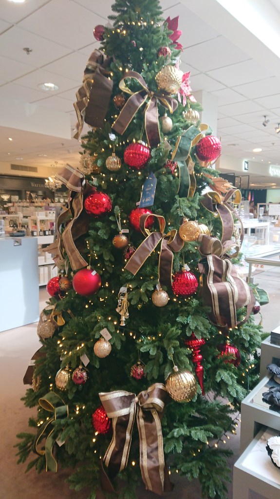 Picture of Christmas tree with red and gold baubles, red and hold baubles and wreath with ponsiettia and red berries.